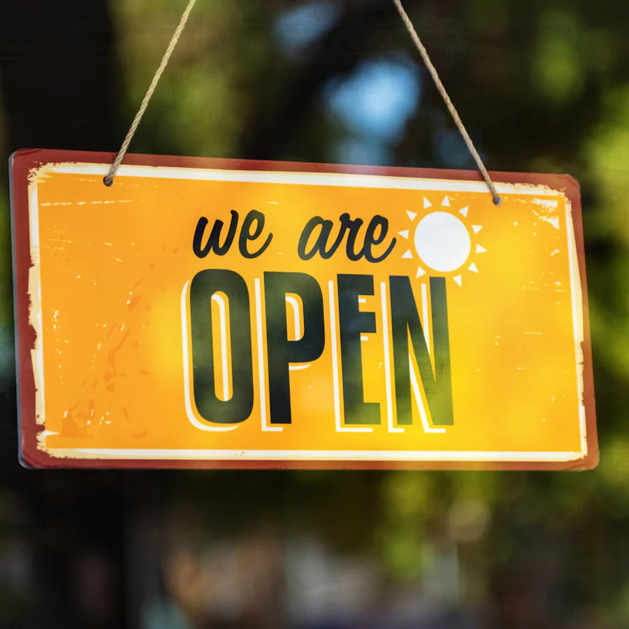 Une pancarte jaune « we are open » accrochée à une vitrine
